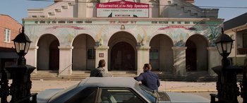 Movie still from “22 Jump Street” (2014), directed by Phil Lord – Two people sitting in a car in front of a church; Wide shot, High angle