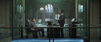 Movie still from “22 Jump Street” (2014), directed by Phil Lord – Two men sitting in front of a laptop computer in front of stained glass windows; Wide shot, Low angle