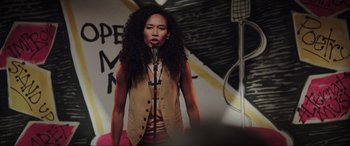 Movie still from “22 Jump Street” (2014), directed by Phil Lord – A woman standing on a stage holding a microphone; Medium shot, Over the shoulder angle