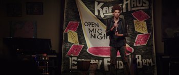 Movie still from “22 Jump Street” (2014), directed by Phil Lord – A man standing on a stage holding a microphone; Wide shot, Over the shoulder angle