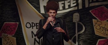 Movie still from “22 Jump Street” (2014), directed by Phil Lord – A man in a black shirt is singing into a microphone; Medium shot, Low angle