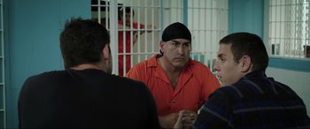 Movie still from “22 Jump Street” (2014), directed by Phil Lord – A group of men sitting in front of a jail cell; Medium shot, Over the shoulder angle