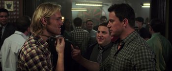 Movie still from “22 Jump Street” (2014), directed by Phil Lord – A group of men standing in front of each other in a room; Medium shot, Over the shoulder angle
