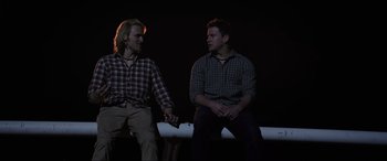 Movie still from “22 Jump Street” (2014), directed by Phil Lord – Two men sitting on a bench in the dark holding hands; Medium shot, Low angle