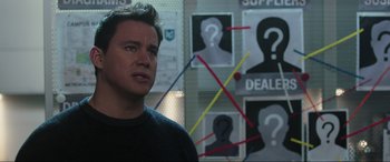Movie still from “22 Jump Street” (2014), directed by Phil Lord – A man standing in front of a bunch of posters; Close Up shot, Over the shoulder angle