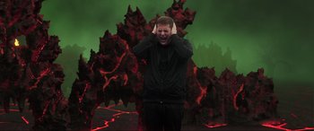 Movie still from “22 Jump Street” (2014), directed by Phil Lord – A man holding his hands to his ears in front of a green background; Medium shot, High angle