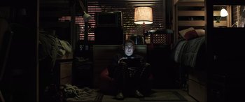 Movie still from “22 Jump Street” (2014), directed by Phil Lord – A man sitting on a chair in a dark room; Wide shot, High angle