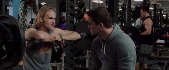 Movie still from “22 Jump Street” (2014), directed by Phil Lord – Two young men in a gym talking to each other; Medium shot, Over the shoulder angle