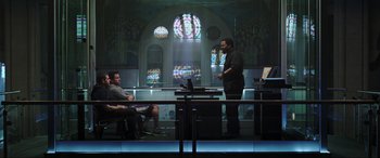 Movie still from “22 Jump Street” (2014), directed by Phil Lord – Two men sitting in front of a computer screen in front of stained glass windows; Wide shot, Over the shoulder angle
