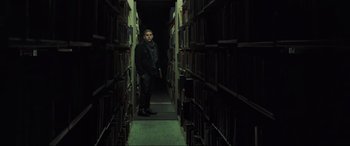 Movie still from “22 Jump Street” (2014), directed by Phil Lord – A man standing in a room filled with books; Medium shot, Low angle