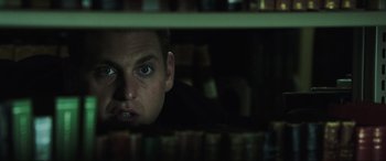 Movie still from “22 Jump Street” (2014), directed by Phil Lord – A man is looking at the camera from behind a shelf; Close Up shot, Low angle