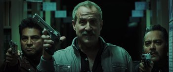 Movie still from “22 Jump Street” (2014), directed by Phil Lord – A person holding a gun in a dark room; Close Up shot, Low angle