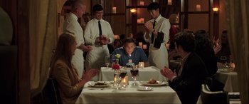 Movie still from “22 Jump Street” (2014), directed by Phil Lord – A group of people sitting at a table with a lit candle; Medium shot, High angle