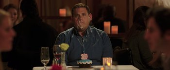 Movie still from “22 Jump Street” (2014), directed by Phil Lord – A man sitting at a table with a cake on his face; Medium shot, Over the shoulder angle