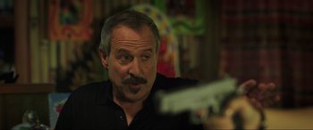 Movie still from “22 Jump Street” (2014), directed by Phil Lord – A person holding a gun; Close Up shot, Over the shoulder angle