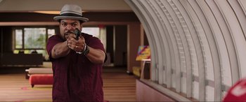 Movie still from “22 Jump Street” (2014), directed by Phil Lord – A man holding a gun in a room with arches; Medium shot, Over the shoulder angle