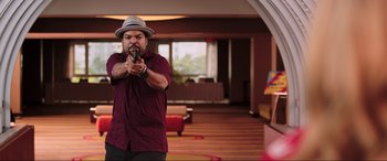 Movie still from “22 Jump Street” (2014), directed by Phil Lord – A man holding a video game controller in a room; Medium shot, Over the shoulder angle