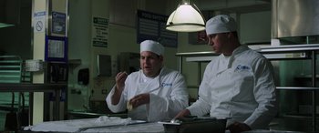 Movie still from “22 Jump Street” (2014), directed by Phil Lord – Two chefs in a kitchen preparing food for a meal; Medium shot, Over the shoulder angle