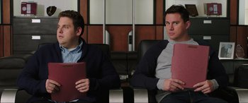 Movie still from “22 Jump Street” (2014), directed by Phil Lord – Two men sitting next to each other holding papers; Medium shot, Low angle