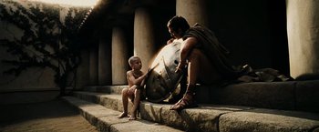 Movie still from “300” (2006), directed by Zack Snyder – A man and a boy are sitting on some steps; Medium shot, High angle