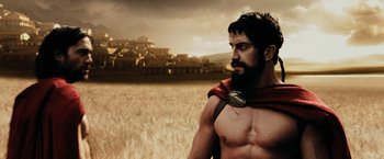 Movie still from “300” (2006), directed by Zack Snyder – A man with a beard wearing a red and black scarf; Medium shot, Low angle