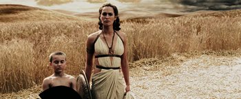 Movie still from “300” (2006), directed by Zack Snyder – A woman in a dress standing in a field; Medium shot, Over the shoulder angle