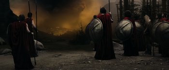 Movie still from “300” (2006), directed by Zack Snyder – A man in a red cloak and a red cape holding a shield; Wide shot, Low angle