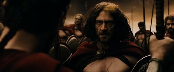 Movie still from “300” (2006), directed by Zack Snyder – A person with a beard wearing a red cape; Medium shot, Over the shoulder angle