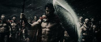 Movie still from “300” (2006), directed by Zack Snyder – A man holding a shield in the rain; Medium shot, Low angle