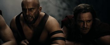 Movie still from “300” (2006), directed by Zack Snyder – A man and a woman are sitting on a bench; Close Up shot, Low angle