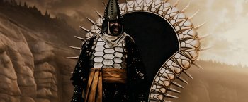 Movie still from “300” (2006), directed by Zack Snyder – A man dressed in armor standing in front of an arch; Medium shot, Low angle