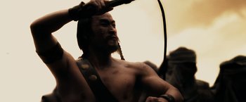 Movie still from “300” (2006), directed by Zack Snyder – A man with long hair is holding a blow dryer in his hand; Close Up shot, Low angle