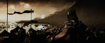 Movie still from “300” (2006), directed by Zack Snyder – A man in chains is looking out over the water; Extreme Wide shot, High angle
