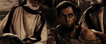 Movie still from “300” (2006), directed by Zack Snyder – A man with a beard sitting next to another man with a beard; Close Up shot, Over the shoulder angle