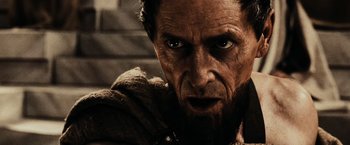 Movie still from “300” (2006), directed by Zack Snyder – An old man with a beard stares at the camera; Close Up shot, Low angle