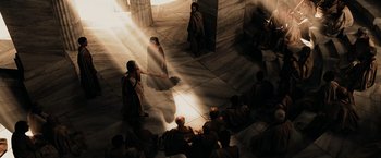 Movie still from “300” (2006), directed by Zack Snyder – A group of people sitting in a room with light shining on them; Extreme Wide shot, High angle