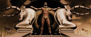 Movie still from “300” (2006), directed by Zack Snyder – A man in chains standing on top of a statue; Wide shot, Low angle