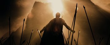 Movie still from “300” (2006), directed by Zack Snyder – A man with a cape and a sword standing in front of the sun; Extreme Wide shot, Low angle