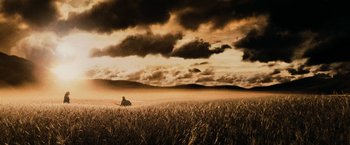 Movie still from “300” (2006), directed by Zack Snyder – A person sitting in a field under a cloudy sky; Extreme Wide shot, Low angle