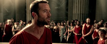 Movie still from “300: Rise of an Empire” (2014), directed by Noam Murro – A man in a red robe is in front of a group of people; Close Up shot, Over the shoulder angle
