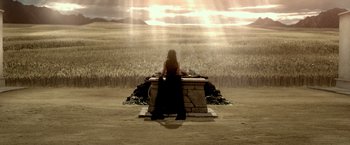 Movie still from “300: Rise of an Empire” (2014), directed by Noam Murro – A woman sitting on top of a stone bench in front of a field; Extreme Wide shot, High angle