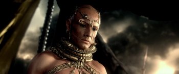 Movie still from “300: Rise of an Empire” (2014), directed by Noam Murro – A man in chains and gold jewelry is posing for a picture; Close Up shot, Low angle