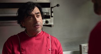 A man in a red shirt is standing in a kitchen