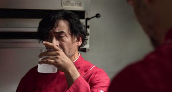 Movie still from “40 Years Young” (2022), directed by Pietro Loprieno – A man in a red shirt is drinking a glass; Close Up shot, Low angle