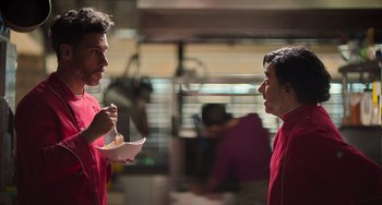 Movie still from “40 Years Young” (2022), directed by Pietro Loprieno – Two men in red shirts are talking to each other; Medium shot, Over the shoulder angle