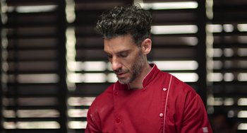 Movie still from “40 Years Young” (2022), directed by Pietro Loprieno – A man in a red chef's jacket looking down; Close Up shot, Low angle