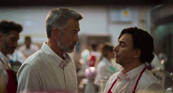 Movie still from “40 Years Young” (2022), directed by Pietro Loprieno – Two men standing next to each other in a kitchen; Close Up shot, Over the shoulder angle