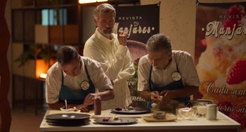 Movie still from “40 Years Young” (2022), directed by Pietro Loprieno – A group of men sitting at a table with food on it; Medium shot, High angle