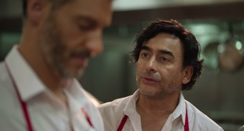 Movie still from “40 Years Young” (2022), directed by Pietro Loprieno – A man in a white shirt and a man in a red apron; Close Up shot, Over the shoulder angle