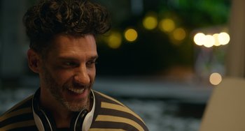 Movie still from “40 Years Young” (2022), directed by Pietro Loprieno – A person wearing headphones; Close Up shot, Over the shoulder angle